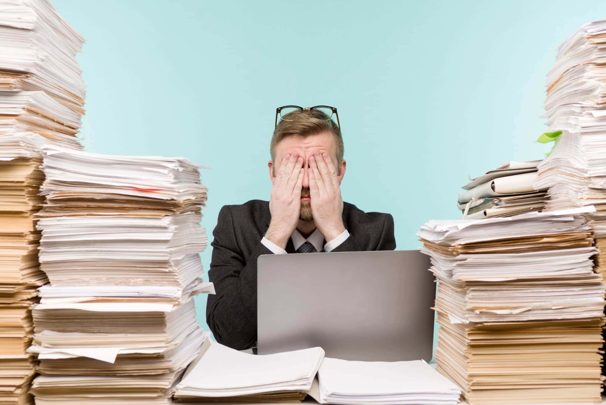 Image of an overhelmed man surrounded by papers Image of an overhelmed man surrounded by papers